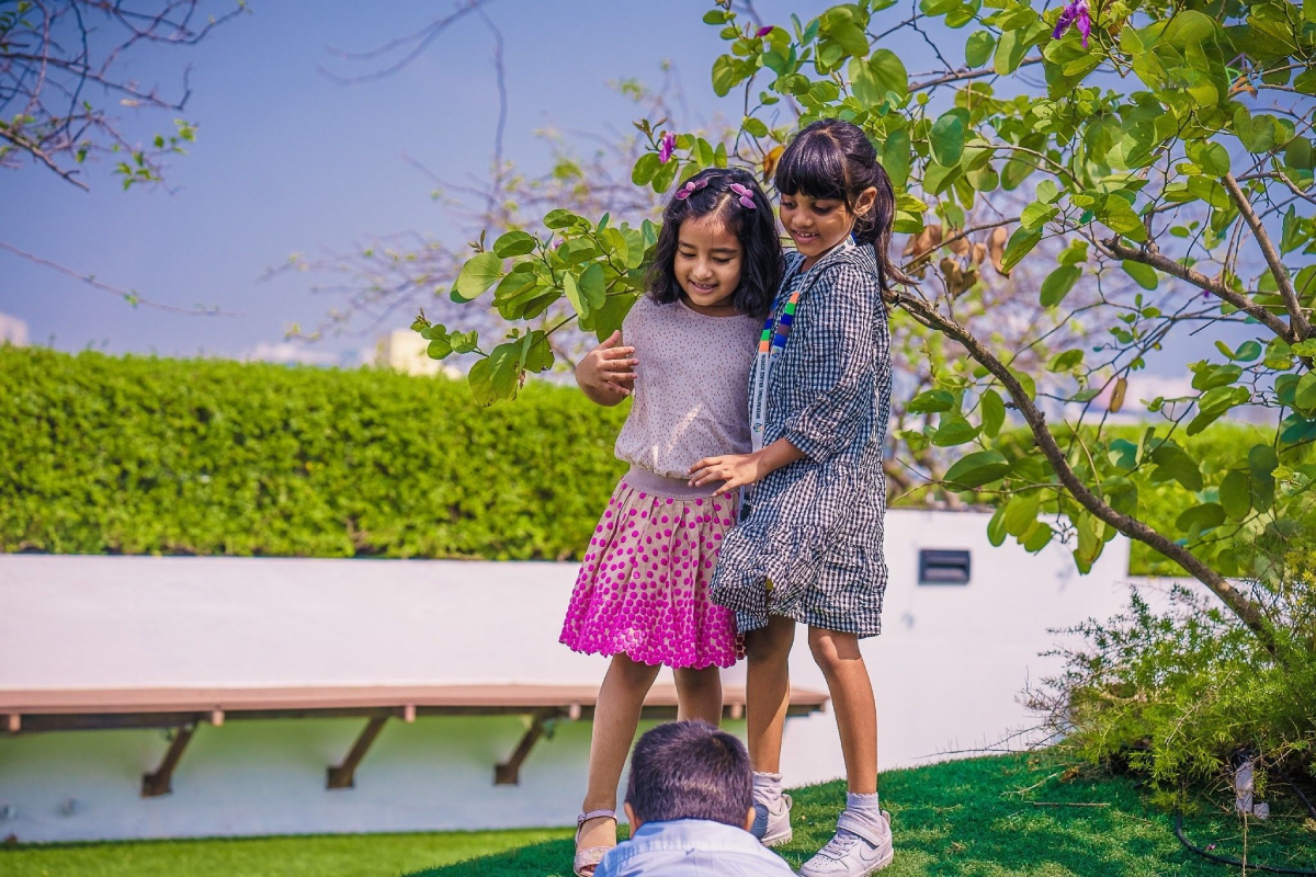 Two girls play in the lawn area next to the dining space.