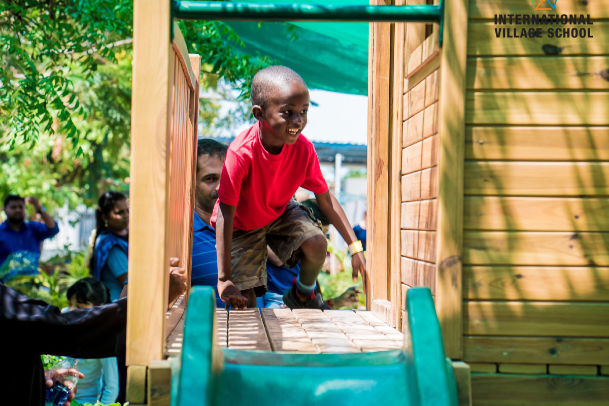 A happy small boy playing in the play area of the school.