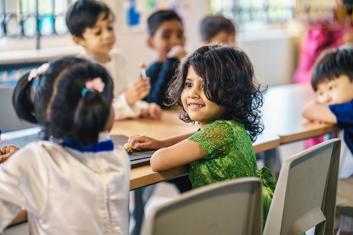 Enthusiastic children with chocolates in their hand, seated inside the classroom.